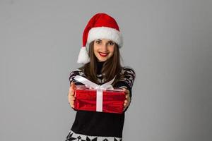 femme en pull chaud et bonnet de noel avec cadeau rouge photo