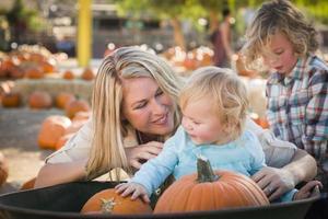 jeune famille profite d'une journée au champ de citrouilles photo