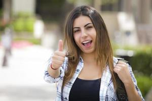 Étudiante de race mixte sur le campus de l'école avec les pouces vers le haut photo