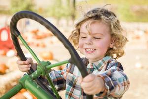 adorable jeune garçon jouant sur un vieux tracteur à l'extérieur photo