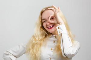 superbe modèle féminin aux cheveux courts posant avec l'expression du visage de baiser sur le fond. portrait en gros plan d'une fille européenne élégante debout avec un signe de paix devant le mur photo