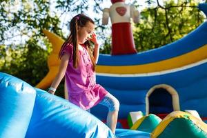 petite fille heureuse s'amusant beaucoup sur un château de saut pendant la glissade. photo