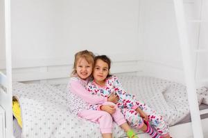 deux petites soeurs adorables souriantes dans un lit blanc, haut, vue photo