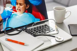 lieu de travail du médecin avec ordinateur portable et stéthoscope et ordinateur portable sur la vue de dessus de table blanche photo