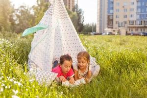 concept d'enfance et d'hygge - petites filles heureuses jouant dans une tente pour enfants photo