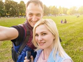 photo en gros plan d'un jeune couple prenant un selfie en plein air. jeune homme prenant une photo avec sa petite amie. heureux couple souriant prenant un selfie dans une journée d'été