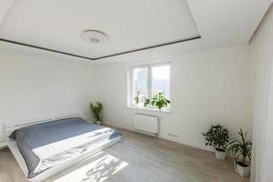 chambre blanche avec éléments en briques, balcon, lit double, bureau photo