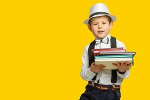 heureux garçon souriant dans des verres avec le pouce vers le haut va à l'école pour la première fois. enfant avec sac d'école et livre. enfant à l'intérieur de la salle de classe avec tableau noir sur fond. retour à l'école. photo