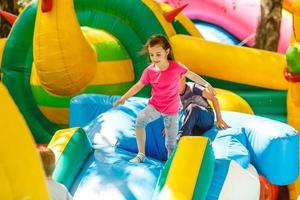 petite fille heureuse s'amusant beaucoup sur un château de saut pendant la glissade. photo