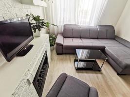 salon de luxe lumineux avec canapé, table basse noire, cheminée et télévision photo