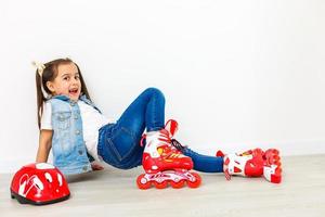 un adorable enfant d'âge préscolaire souriant bien que tombé en apprenant à faire du patin à roulettes. sur un fond blanc. photo