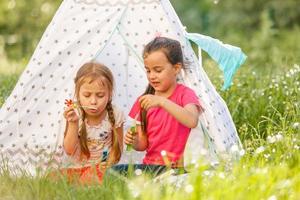 concept d'enfance et d'hygge - petites filles heureuses jouant dans une tente pour enfants photo