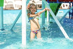 petite fille jouant dans la piscine extérieure sautant dans l'eau pendant les vacances d'été sur l'île de la plage tropicale. enfant apprenant à nager dans la piscine extérieure du complexe de luxe. photo