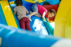 petite fille heureuse s'amusant beaucoup sur un château de saut pendant la glissade. photo