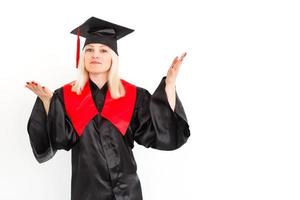 une étudiante diplômée heureuse et excitée se tient debout dans le manteau, souriant et regardant la caméra photo