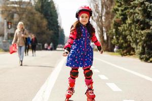 Petite jolie fille sur patins à roulettes en casque dans un parc photo