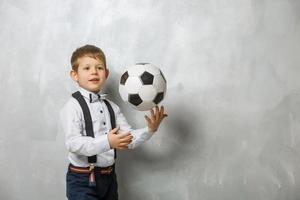 petit garçon avec un ballon de football sur fond gris photo