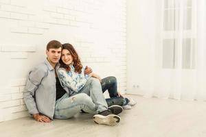 l'homme et la femme heureux s'assoient sur le fond du mur blanc photo