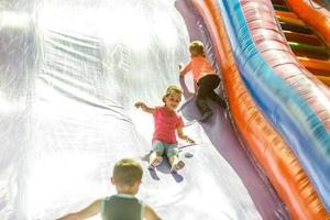 petite fille heureuse s'amusant beaucoup sur un château de saut pendant la glissade. photo