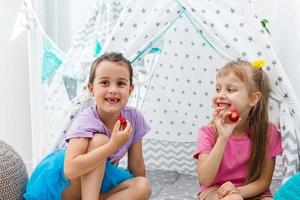 deux petites filles mignonnes assises et mangeant des fraises. photo