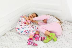 deux petites soeurs adorables souriantes dans un lit blanc, haut, vue photo