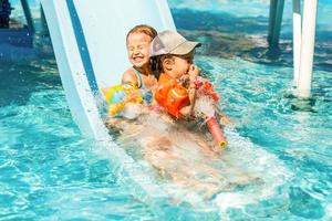 enfant sur toboggan aquatique au parc aquatique. vacances d'été. photo