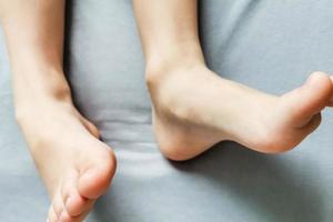 pieds nus des enfants. les pieds nus de l'enfant sur un lit gris photo