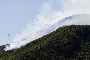 hélicoptère de lutte contre les incendies laissant tomber de l'eau sur un feu de forêt à la montagne à sant'antonio abate, campanie, italie. photo