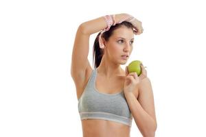 jeune fille fitness haut gris leva la main et garde la pomme verte en gros plan photo