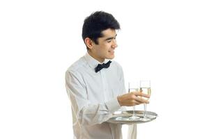 souriant charmant serveur prend un verre de vin avec un plateau photo