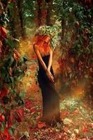 dame de beauté élégance posant dans la forêt avec une couronne de hop sur la tête photo
