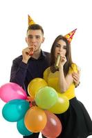 jeune homme et jolie fille soufflent des cornes et portent des ballons colorés photo