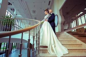 jeune couple juste marié en costumes de mariage serrant sur une échelle photo