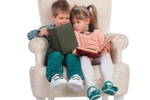 les enfants sont assis sur une chaise avec des livres photo