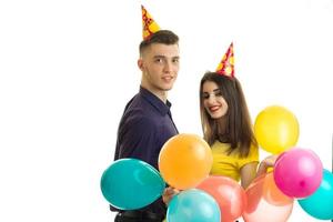 joyeux jeune couple fête son anniversaire avec de gros ballons et des cônes sur la tête et souriant photo