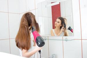 fille devant le miroir sèche les cheveux photo