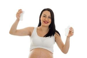 Brunette enceinte future mère avec de petites chaussettes dans ses mains souriant à la caméra isolé sur fond blanc photo