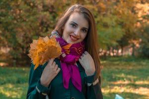 jolie jeune fille garde les feuilles dans sa main et sourit photo