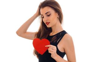 Jolie jeune femme brune aux lèvres rouges et coeur en mains isolé sur fond blanc photo