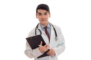 jeune beau médecin en uniforme bleu avec stéthoscope sur son cou prendre des notes isolé sur fond blanc photo