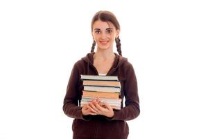 Smiling teen girl with pigtails smortit à droite et détient de nombreux livres photo