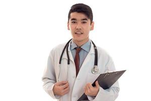 Portrait of funny young brunette male doctor en uniforme avec stéthoscope posant isolé sur fond blanc photo