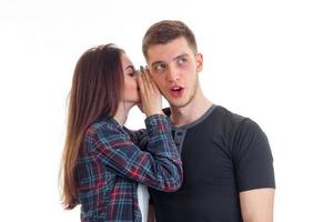 une jeune fille aux cheveux longs a dit quelque chose dans l'oreille du gars couvrant les mains et il est surpris et ouvre la bouche photo