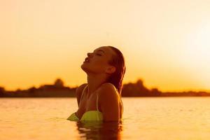 jeune femme sexuelle dans la mer au coucher du soleil chaud photo