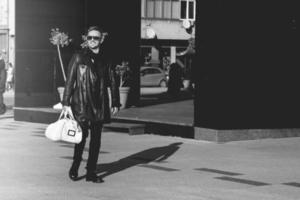 photo en noir et blanc d'un beau modèle masculin portant des lunettes de soleil marchant dans la rue