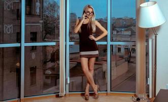 portrait de mode d'une jeune femme blonde gaie parlant au téléphone près de la grande fenêtre photo