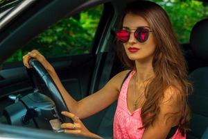 portrait d'une superbe jeune fille en lunettes de soleil miroir pour conduire une voiture photo
