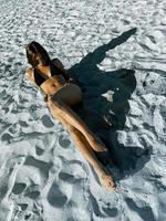 charmante jeune femme prenant un bain de soleil sur le sable blanc photo