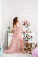 belle femme enceinte en robe rose à la maison photo