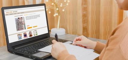 une femme faisant des achats en ligne, qui paie en ligne, sur un ordinateur portable, assise dans le salon, à la maison. concept de transfert d'argent numérique, de banque et de commerce électronique. photo